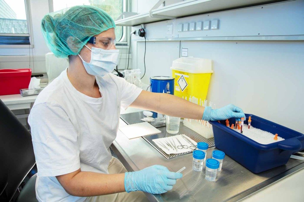 Eine Laborantin einer Berliner pharmazeutischen Firma legt Reagenzgläser in Eis zum Kühlen